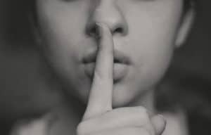 Frau legt ihren Finger auf die Lippen, damit man sich bei FOMO nicht selbst belügt